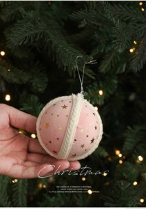 Close-up of pink velvet Christmas ball ornament with gold stars and woven cord detail