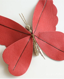 Close-up of red Christmas butterfly clip with gold glitter details and metal fastener