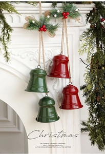 Detail of red and green metal Christmas bells with pine needles on a white mantel