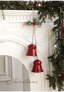 Detail of red Christmas bells with pine needles and burlap bow on white fireplace