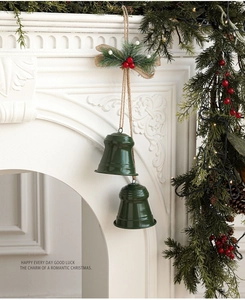 Detail of green metal Christmas bells hanging on a rope with berries and burlap bow