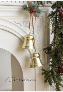 Close-up of golden metal Christmas bells with rustic hemp rope and festive pine leaf decor