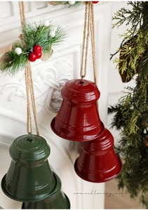 Close-up of festive red and green metal bells with twine rope on a white mantel