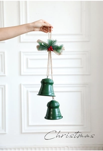 Close-up of green metal Christmas bells with red berries and burlap bow decoration