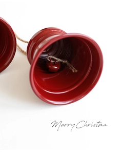 Close-up of a red metal Christmas bell with rustic twine and Merry Christmas text