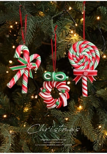 Detail of red and green candy cane ornaments hanging on a Christmas tree with warm lights