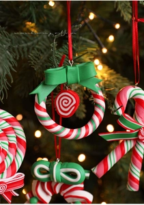 Close-up of red and green clay candy canes and wreaths on a lit Christmas tree branch