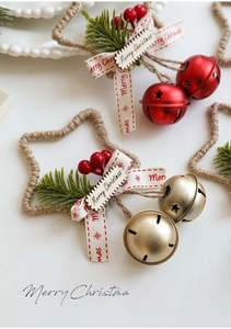 Dettaglio di stella di Natale appesa con campanelli, aghi di pino e bacche rosse