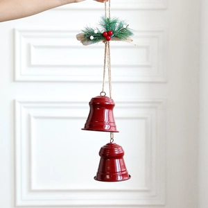 Red Christmas bells decoration with artificial pine needles and jute bow on a hanging rope
