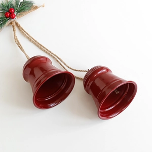 Red Christmas bell ornaments with pine needles and burlap bow on rustic jute rope