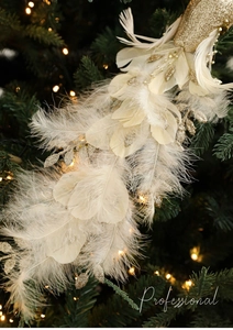 Detail of glittery white feather bird ornament with gold sequins on Christmas tree branch