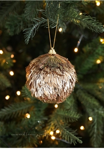Détail de boule de Noël à franges champagne doré suspendue au sapin avec lumières chaudes