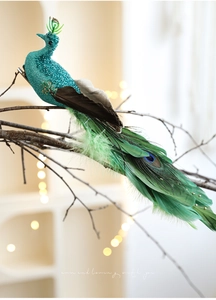 Detailed peacock ornament with real feathers and teal glitter on a wooden branch