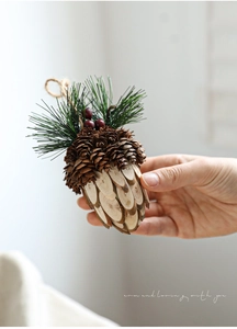 Détail d'un ornement de Noël en pomme de pin en bois avec aiguilles et baies