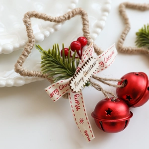 Ciondolo a stella di Natale con campanelli rossi bacche e rami di pino su piatto