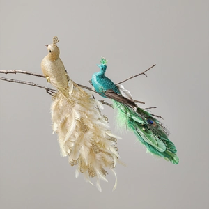 Artificial glitter peacock ornaments with white and green feathers on tree branches