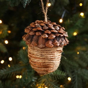 Grande suspension pomme de pin en bois avec corde en jute sur un sapin de Noël illuminé