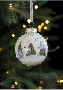 Close-up of clear Christmas bauble with faux snow, silver studs and sparkling rhinestones