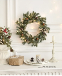 Close-up of Christmas wreath with warm LED lights, pine cones and Merry Christmas sign