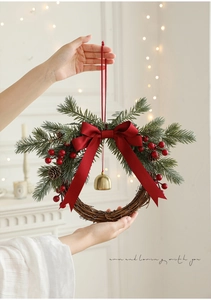 Detail of Christmas wreath with red bow, golden bell and berries held by hand