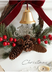 Close-up of Christmas wreath with red velvet bow, gold bell, pine cones and berries