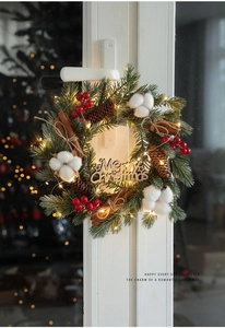 Detail of Christmas wreath with pine cones, red berries, LED lights and Merry Christmas sign