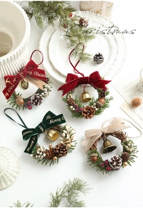 Detailed view of four Christmas wreaths with bells and pine cones on a white background
