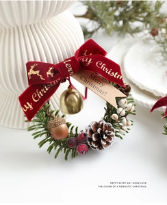 Detail of Christmas wreath featuring red velvet bow, pine cones, berries, and golden bell