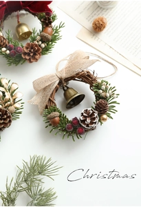 Detail of Christmas wreath with pine cones red berries and golden bells on white background