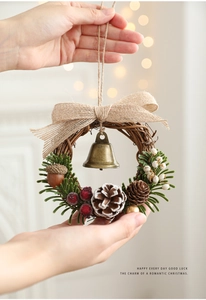 Detail of Christmas wreath with pine cones and bells held against festive lights