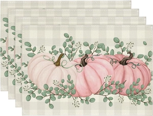 Detail showing stacked linen placemats with pink pumpkin pattern and eucalyptus leaves