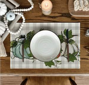 Detail of linen placemat with pumpkin pattern on a rustic wooden dining table