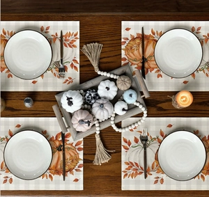 Detail of linen placemats featuring pumpkin and maple leaf patterns for Thanksgiving