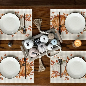 Set of 4 linen Thanksgiving placemats with pumpkin and fall leaf patterns on wood table