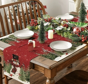 Close-up of linen Christmas placemat with snowman, red bird and evergreen tree prints