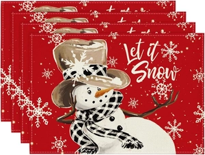 Close-up of four red linen Christmas placemats with Let it Snow text and snowman pattern