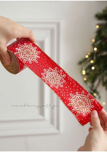 Close-up of red Christmas ribbon with white snowflakes and golden edges for gift wrapping