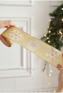 Close-up of gold Christmas ribbon with white snowflake patterns and sparkling glitter