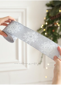 Detail showing silver Christmas ribbon with white snowflake patterns and glitter dots