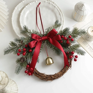 Christmas rattan wreath with red berries, pine cones, bow and golden bell decoration