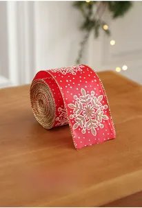 Detail of red Christmas ribbon with white snowflakes and golden glitter edges on wood