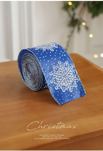 Close-up of blue Christmas ribbon with silver snowflake patterns and stitched edges