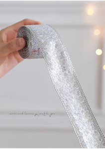 Detailed macro view of silver sequin ribbon roll for Christmas gift wrapping and decor