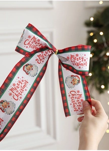 Dettaglio di un fiocco natalizio in iuta con Babbo Natale e nastri decorativi a quadri