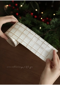 Close-up of champagne Christmas ribbon with gold glitter plaid pattern and holiday decor