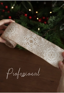 Close-up of champagne Christmas ribbon with white snowflake patterns and satin texture