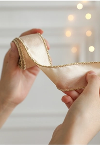 Macro shot of champagne satin ribbon with elegant gold woven edges for gift wrapping