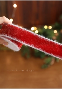 Detail eines roten Weihnachtsbandes mit Goldglitzer und weißem Kunstpelzrand für Geschenke