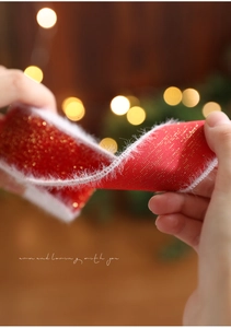 Makroaufnahme von rotem Weihnachtssatinband mit Goldglitzer und weißem Plüschrand
