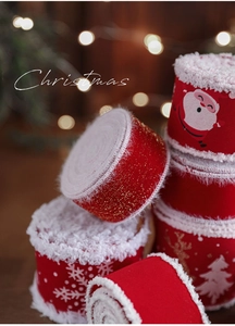 Makro-Detail vom roten Weihnachtsband mit weißem Flauschrand und festlichem Schneeflockenmuster